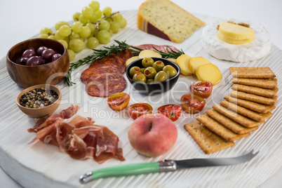 Variety of cheese with grapes, olives, salami, crackers and knife