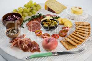 Variety of cheese with grapes, olives, salami, crackers and knife