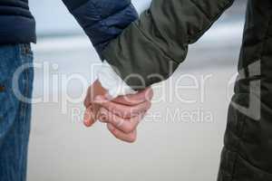 Close-up of couple holding hands on the beach