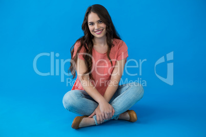 Beautiful woman sitting against blue background