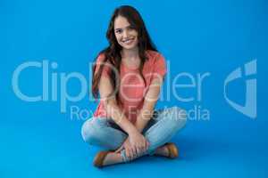 Beautiful woman sitting against blue background