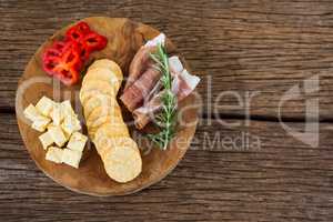 Cheese, red pepper slices, meat and nacho chips on wooden table