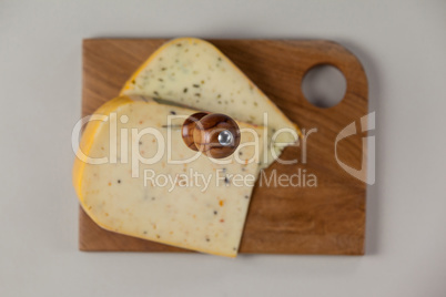 Knife on cheese slice on wooden board