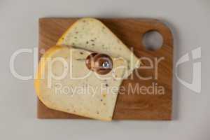 Knife on cheese slice on wooden board