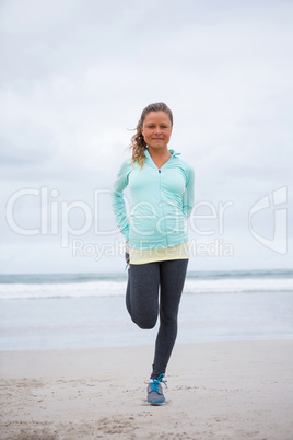 Portrait of woman performing stretching exercise on beach