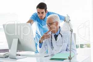 Surgeon and doctor discussing over personal computer