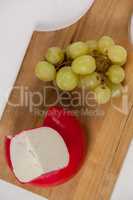 Red cheese and grapes on wooden board