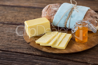 Slices of cheese, bread and fruit jam on wooden board
