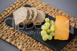 Gouda cheese, bread slices and grapes on slate plate