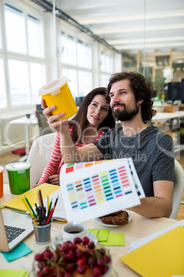 Graphic designers discussing over a container at their desk