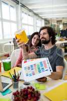 Graphic designers discussing over a container at their desk