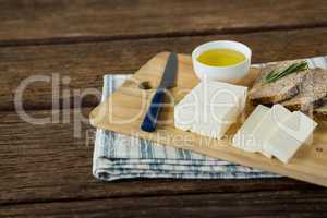 Gouda cheese, brown bread slices and lime juice with knife on chopping board