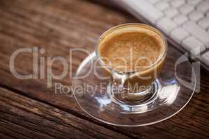 Cup of coffee and keyboard on wooden table