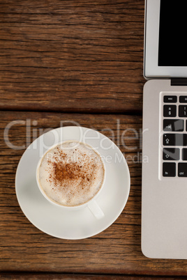 Laptop and cup of coffee on wooden table