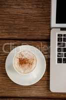 Laptop and cup of coffee on wooden table