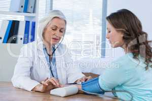 Female doctor checking blood pressure of a patient