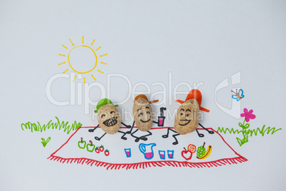 Three happy peanut figurines have picnic on a sunny day