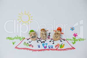 Three happy peanut figurines have picnic on a sunny day