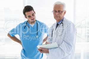 Doctor and surgeon having discussion over clipboard