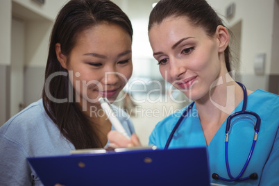 Female nurse assisting patient on clipboard