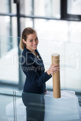 Businesswoman standing at office corridor with chart holder