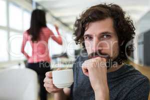 Male graphic designer holding coffee cup at desk