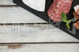 Salami and sliced meat on slate board