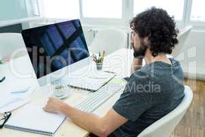 Graphic designer writing in a diary at his desk