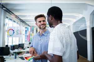 Graphic designer discussing over color swatch with a colleague