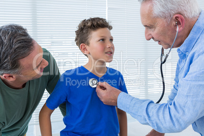 Father looking at son while being examined by doctor