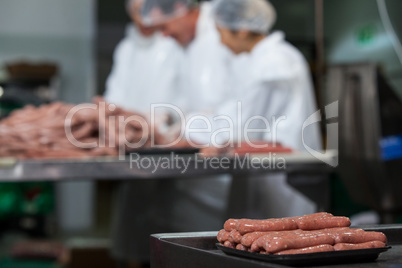 Raw sausages arranged on tray at meat factory