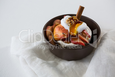 Brie cheese served with fruit slices and walnut in a bowl