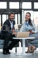 Happy businesspeople sitting with laptop