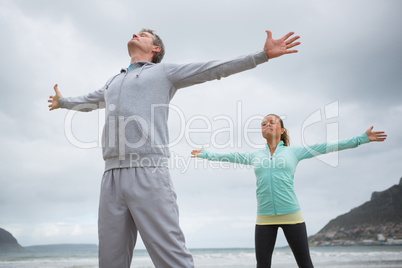 Couple standing with arms outstretched on beach