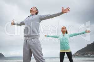 Couple standing with arms outstretched on beach