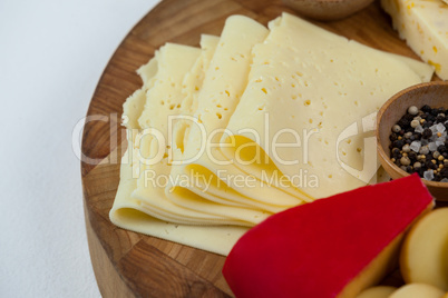 Different types of cheese, cherry tomato, spice and jam on wooden board