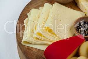 Different types of cheese, cherry tomato, spice and jam on wooden board