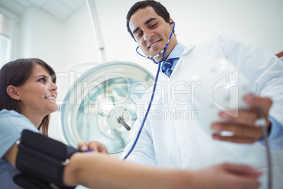 Doctor checking female patient blood pressure