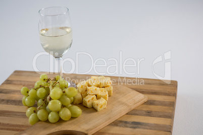Cubes of cheese with grapes and wine glass