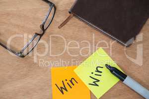 Win written on sticky note with marker, spectacles and diary