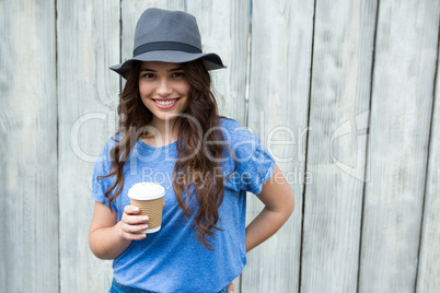 Woman in blue top holding disposable coffee cup