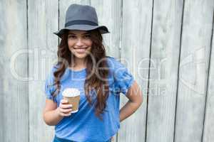 Woman in blue top holding disposable coffee cup