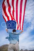 Rear view of man holding american flag on beach