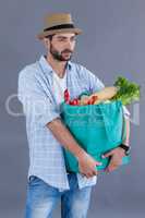 Man in fedora hat carrying groceries bag