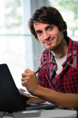 Graphic designer writing in a diary at his desk in office