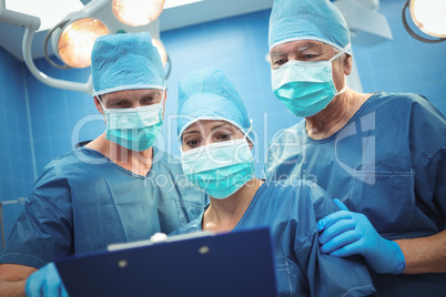 Team of surgeons discussing over clipboard in operation theater