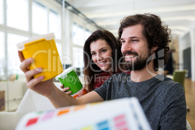 Graphic designers discussing over a container at their desk