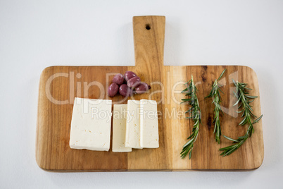 Cheese with olives and rosemary herbs on wooden board