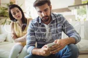 Couple using mobile phone on sofa