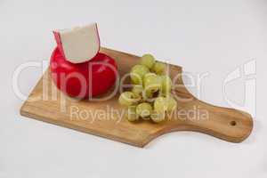 Red cheese and grapes on wooden board